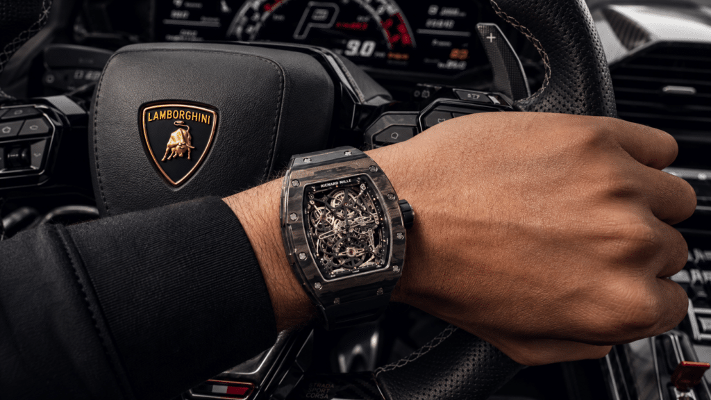 Close-up of a skeleton-style luxury watch on a driver’s wrist while gripping a Lamborghini steering wheel.
